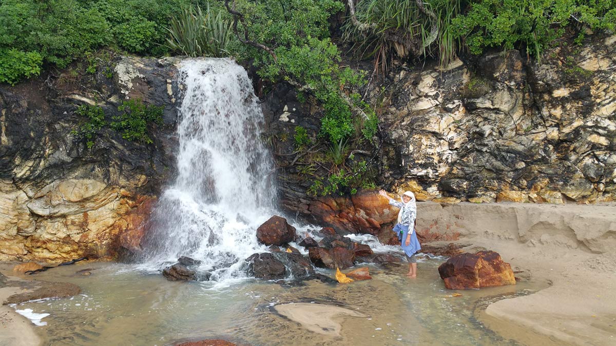 Shantara at waterfall on Onemana beach in New Zealand by Virochana Khalsa